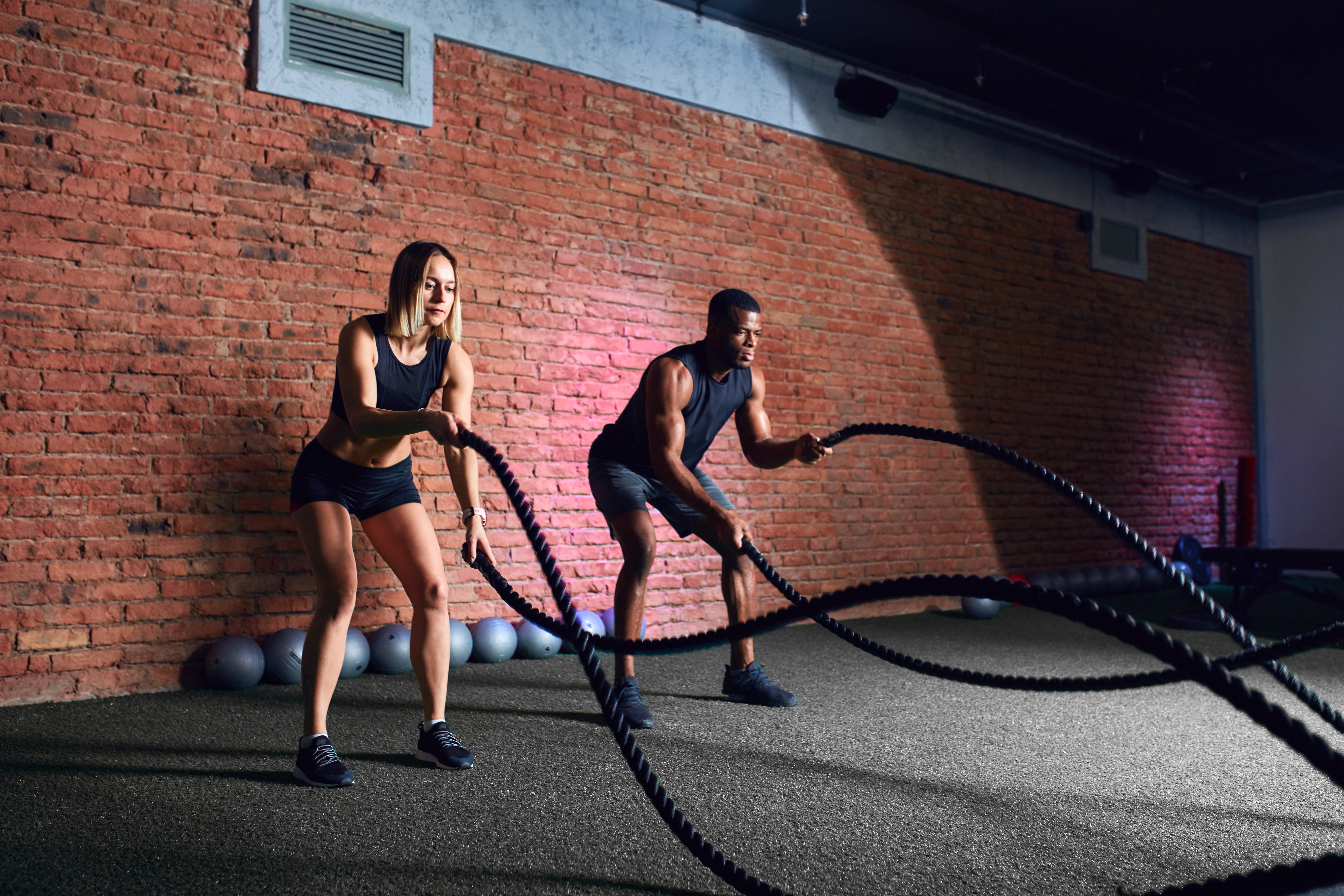 Man and woman using battle ropes for a low impact HIIT cardio exercise